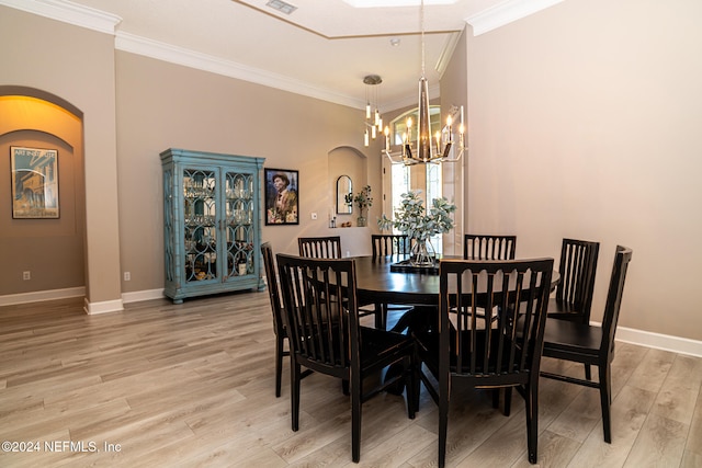 dining area featuring light hardwood / wood-style flooring, ornamental molding, and an inviting chandelier