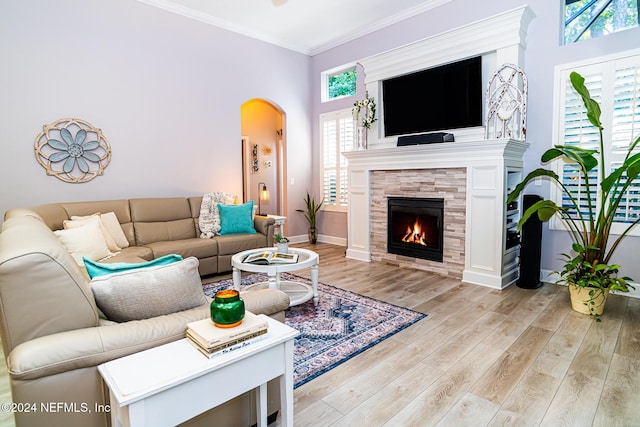 1854 W Cobblestone Ln, Saint Augustine, FL 32092 - living area featuring light wood-style floors, arched walkways, crown molding, a tiled fireplace, and baseboards
