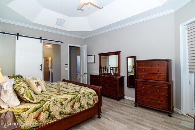 1854 W Cobblestone Ln, Saint Augustine, FL 32092 - bedroom featuring light wood-style flooring, a raised ceiling, a barn door, crown molding, and a ceiling fan