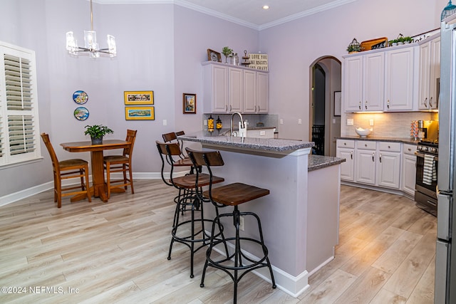 kitchen featuring backsplash, dark stone countertops, ornamental molding, and a breakfast bar area