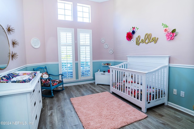 bedroom with a nursery area and dark hardwood / wood-style floors