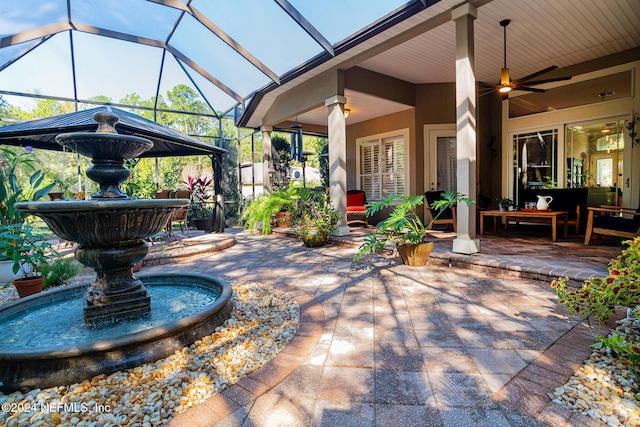 view of patio featuring ceiling fan and glass enclosure