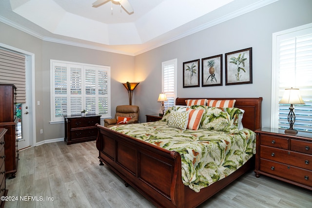 bedroom featuring light hardwood / wood-style flooring, a raised ceiling, ceiling fan, and ornamental molding