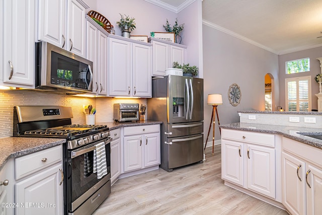 1854 W Cobblestone Ln, Saint Augustine, FL 32092 - kitchen with appliances with stainless steel finishes, crown molding, light wood finished floors, decorative backsplash, and white cabinets