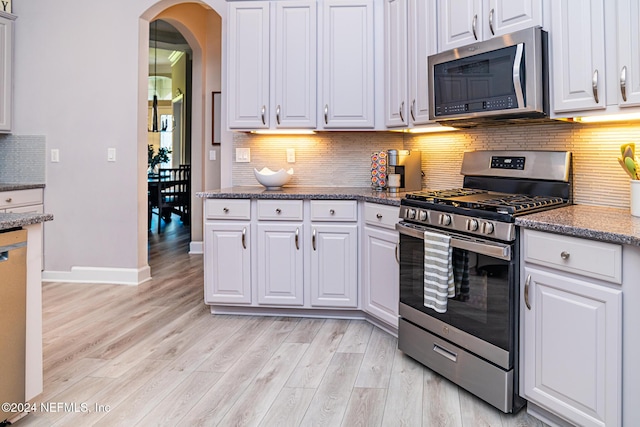 1854 W Cobblestone Ln, Saint Augustine, FL 32092 - kitchen with appliances with stainless steel finishes, light wood-style flooring, arched walkways, and white cabinets