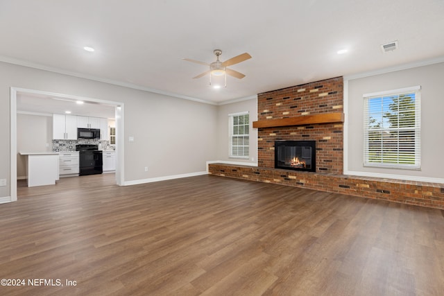 unfurnished living room featuring hardwood / wood-style flooring, ceiling fan, ornamental molding, and a brick fireplace