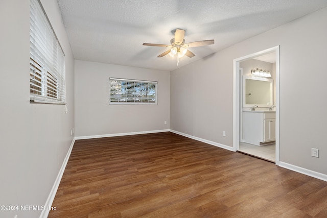 unfurnished bedroom with a textured ceiling, hardwood / wood-style flooring, ceiling fan, and ensuite bathroom