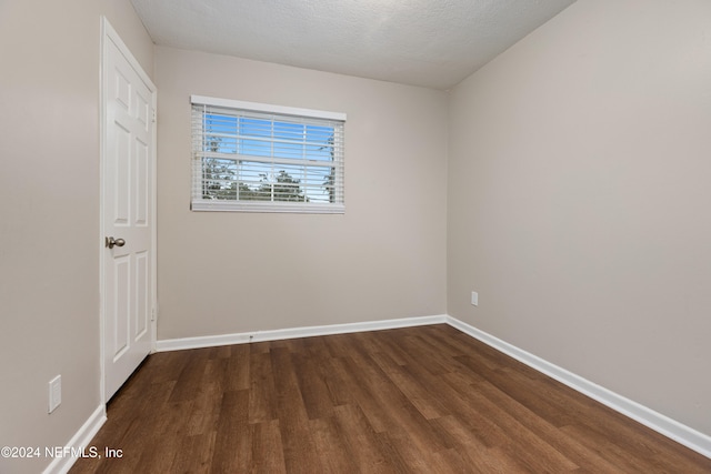 spare room featuring dark hardwood / wood-style floors and a textured ceiling