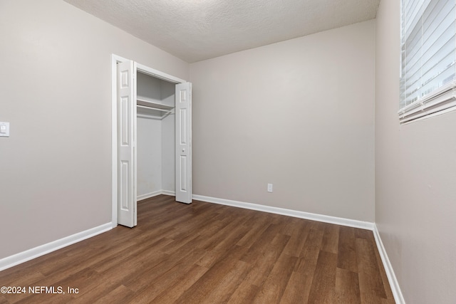 unfurnished bedroom featuring a closet, dark wood-type flooring, and a textured ceiling