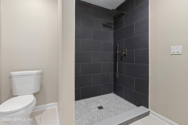 bathroom featuring tile patterned flooring, toilet, and a tile shower