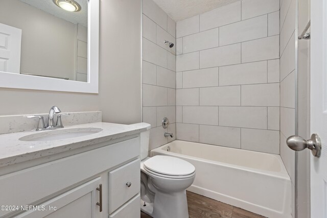 full bathroom featuring tiled shower / bath combo, a textured ceiling, toilet, vanity, and hardwood / wood-style flooring