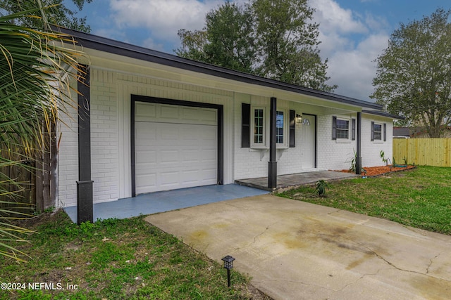 ranch-style house with covered porch, a garage, and a front lawn