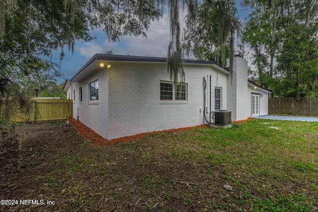 view of side of property with french doors, a yard, and cooling unit