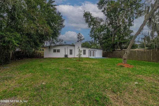 view of yard with central AC and french doors