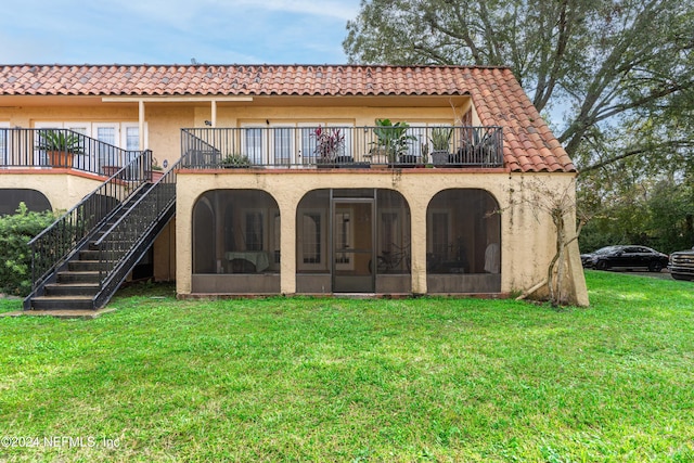 rear view of house with a sunroom, a balcony, and a yard