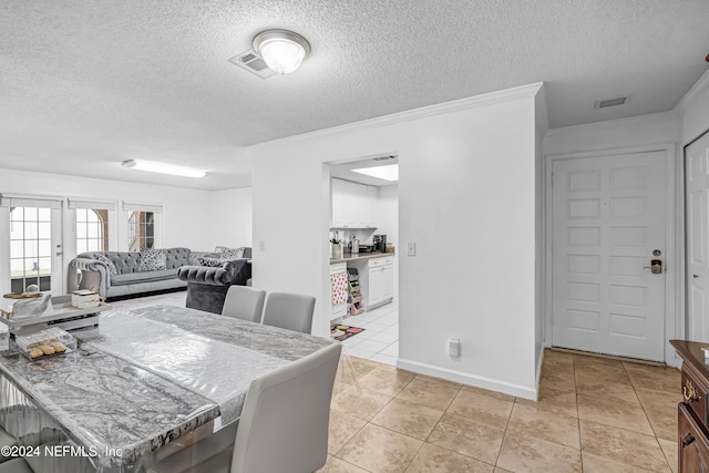 dining space featuring crown molding, light tile patterned flooring, and a textured ceiling