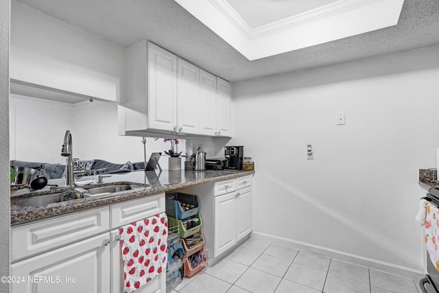 kitchen with sink, light tile patterned floors, dark stone countertops, a textured ceiling, and white cabinets