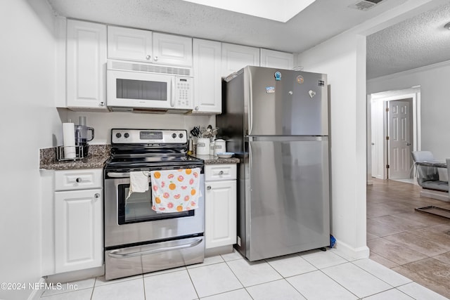 kitchen with light tile patterned floors, white cabinets, stainless steel appliances, and a textured ceiling