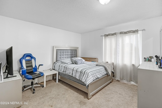 bedroom with light colored carpet and a textured ceiling