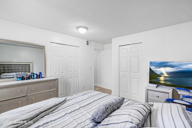 bedroom featuring multiple closets and a textured ceiling