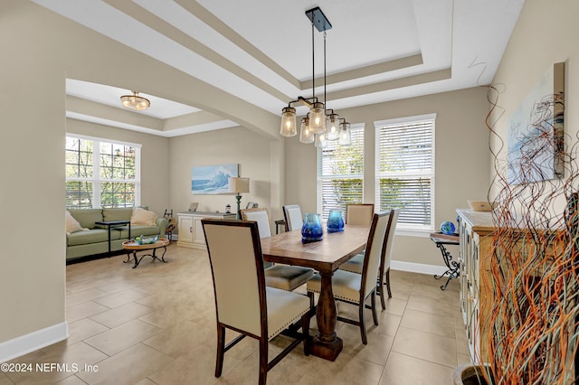 dining space featuring a chandelier, light tile patterned floors, and a tray ceiling