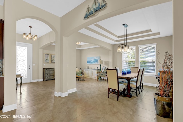 dining area with light tile patterned floors, a raised ceiling, and a notable chandelier