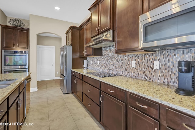 kitchen featuring light stone countertops, light tile patterned floors, stainless steel appliances, and tasteful backsplash