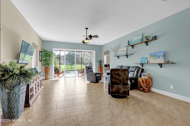 living area with a textured ceiling, ceiling fan, and light tile patterned flooring