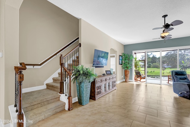 living room featuring ceiling fan, light tile patterned floors, and a textured ceiling