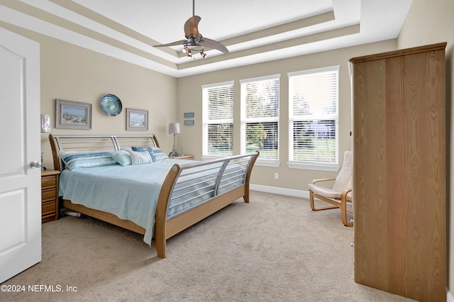 bedroom featuring a tray ceiling, ceiling fan, and light colored carpet