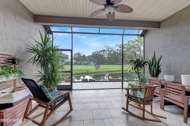 sunroom featuring beamed ceiling, ceiling fan, and a water view