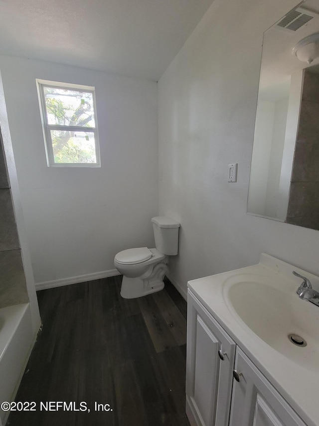 bathroom featuring hardwood / wood-style floors, vanity, toilet, and a bathing tub