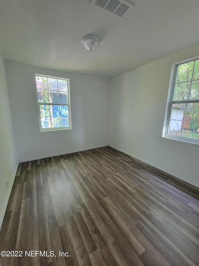 empty room with dark hardwood / wood-style floors and a healthy amount of sunlight