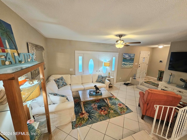 living room featuring ceiling fan, light tile patterned floors, and a textured ceiling