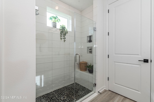 bathroom with an enclosed shower and wood-type flooring