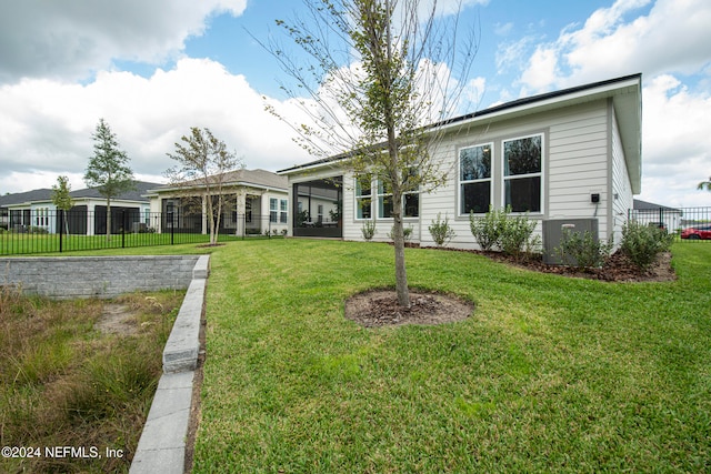 rear view of house featuring central AC and a lawn