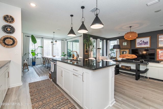 kitchen with white cabinetry, sink, an island with sink, and decorative light fixtures