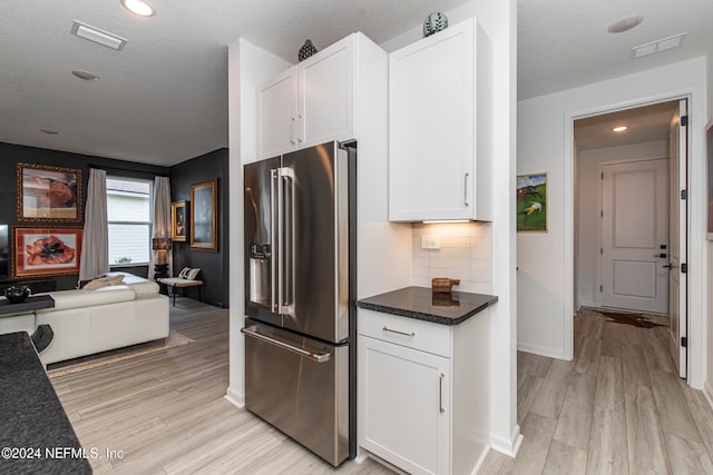 kitchen featuring high quality fridge, decorative backsplash, white cabinets, and light wood-type flooring