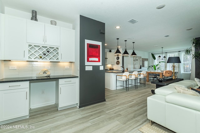 kitchen with decorative backsplash, pendant lighting, light hardwood / wood-style flooring, and white cabinetry