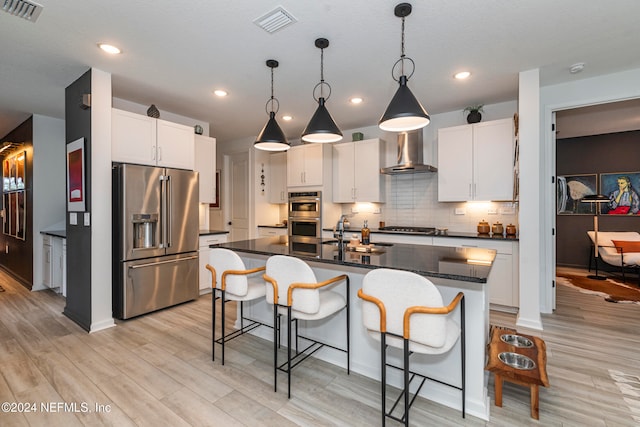 kitchen with appliances with stainless steel finishes, sink, white cabinetry, and an island with sink