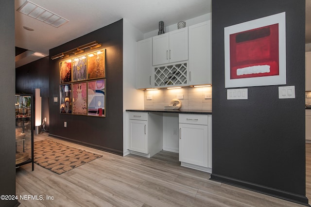 kitchen featuring decorative backsplash, white cabinetry, and light hardwood / wood-style flooring