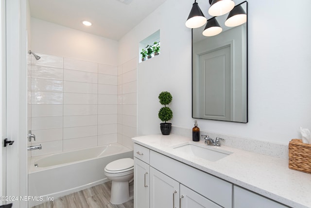 full bathroom featuring hardwood / wood-style floors, vanity, tiled shower / bath combo, toilet, and a notable chandelier