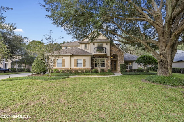 view of front of house featuring a balcony and a front lawn