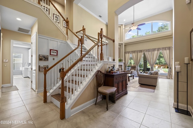 stairs featuring tile patterned flooring, plenty of natural light, ornamental molding, and a high ceiling