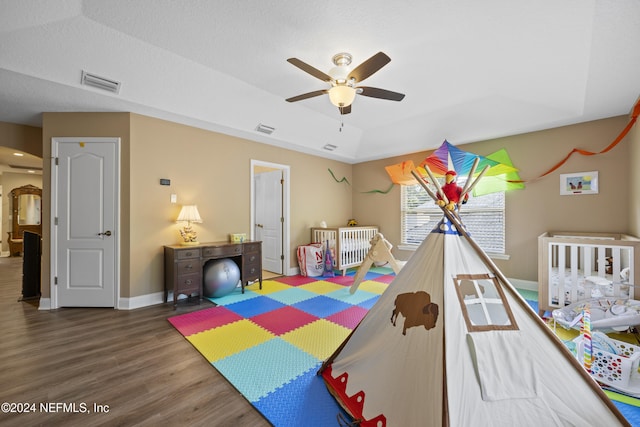 bedroom with a textured ceiling, a raised ceiling, ceiling fan, and dark hardwood / wood-style floors