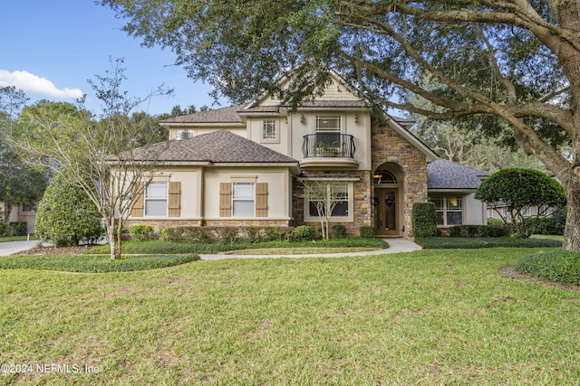 view of front of property featuring a balcony and a front lawn