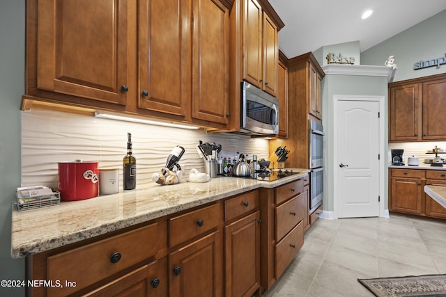 kitchen with light tile patterned floors, light stone countertops, appliances with stainless steel finishes, and tasteful backsplash