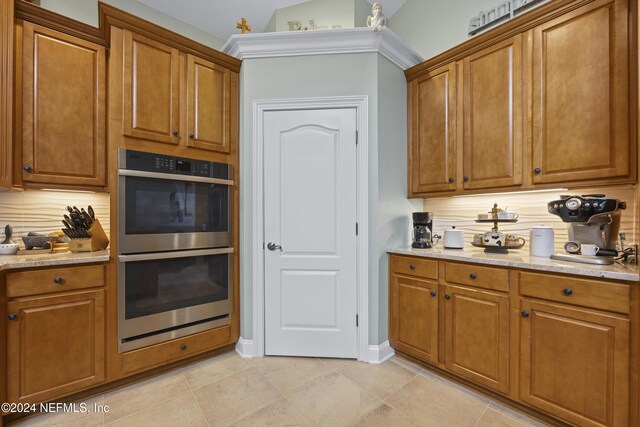 kitchen with tasteful backsplash, light tile patterned floors, double oven, and lofted ceiling