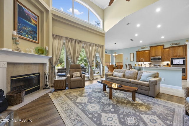 living room with a tile fireplace, a towering ceiling, a wealth of natural light, and dark wood-type flooring