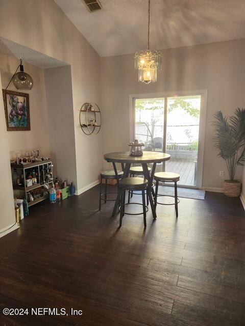 dining space featuring dark hardwood / wood-style flooring, vaulted ceiling, and a notable chandelier